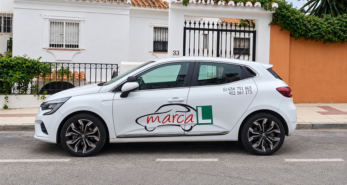 Coche de prácticas de Autoescuela Marca L aparcado en una calle de Benalmádena